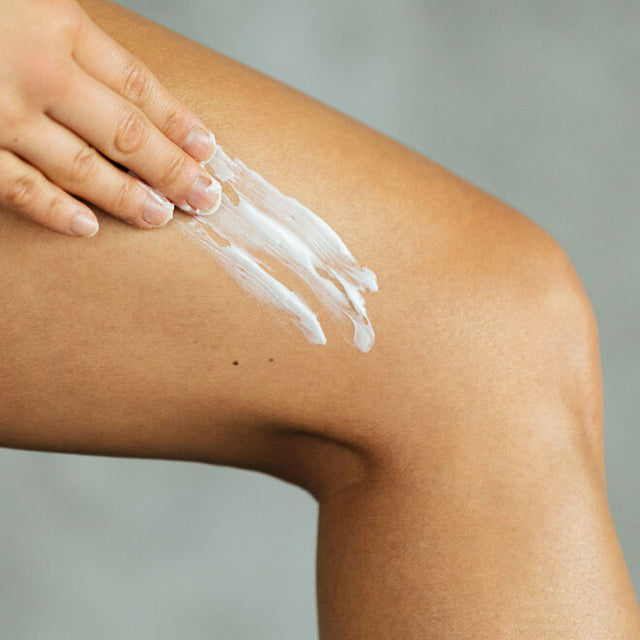 A person applying sleep well body butter to their leg